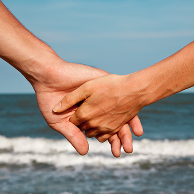 Ein Paar hält Händchen am Meer